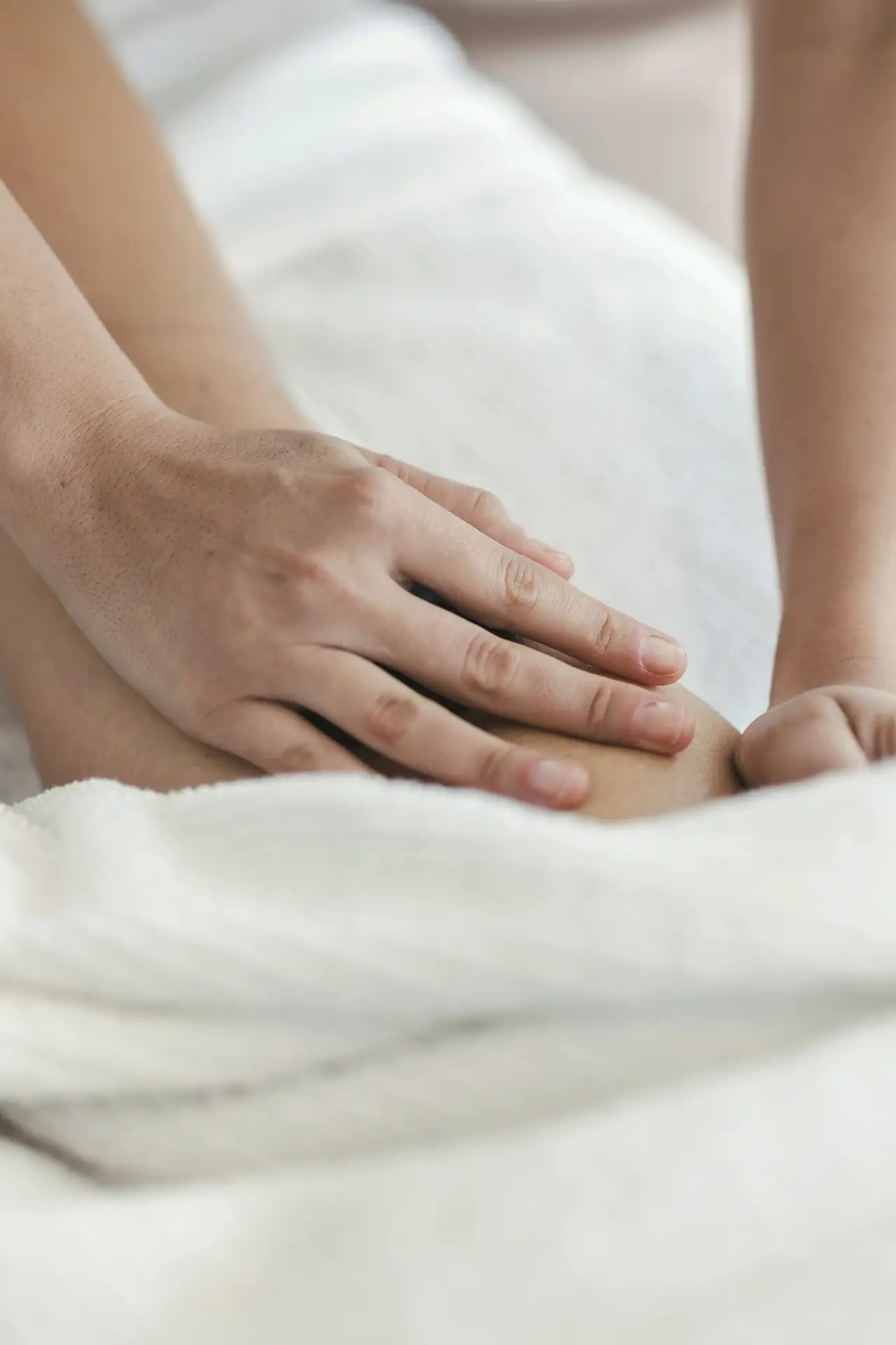 Hands during a massage, white linen
